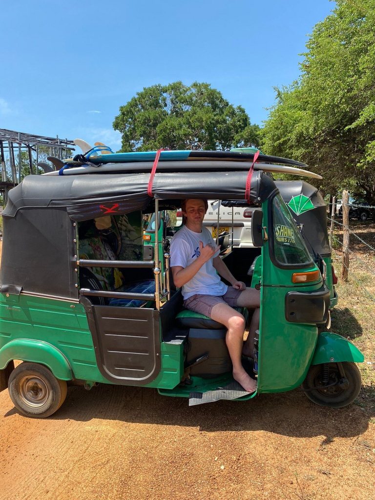 Traveler sitting in a green RideMe tuk tuk with surfboards in Arugam Bay